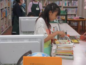 本のバーコードを読み取る女の子