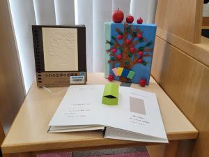 りんごの木とりんごを装飾した本のオブジェと点字図書2冊